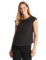 Blusa negra de punto elástico con caída fluida, cuello redondo y apliques de tachas doradas circulares en el cuello y los hombros. Tiene manga casquillo y ruedo redondeado.