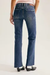 Pantalón jean de corte bootcut, color azul con lavado y efecto desgastado, de tiro medio y con bordes deshilachados en el bajo.