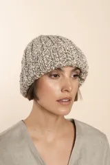 Gorro tejido a mano en punto grueso, con diseño de canalé y textura jaspeada en tonos neutros.