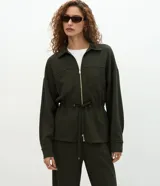 Campera tipo parka color verde oscuro, confeccionada en modal con cierre frontal metálico, cuello camisero, bolsillos frontales y cordón ajustable en la cintura.