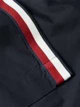 Camisa de manga corta azul marino con cierre de botones, bolsillo en el pecho y rayas rojas y blancas en los hombros.