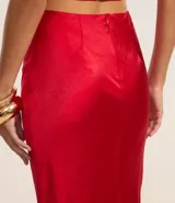 Pollera larga tipo new midi confeccionada en satén rojo, con cierre por cremallera en la cintura y detalle de encaje en la parte trasera.