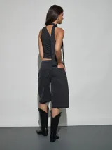 Bermuda de denim negro con tiro medio, bolsillos frontales decorados con strass y apliques de pedrería, y terminación desmechada en las piernas.