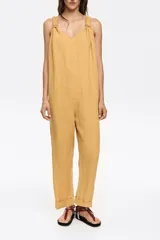 Mono largo de corte recto confeccionado en lino, con escote redondeado y tirantes con detalle de nudo ajustable. Presenta diseño de espalda nadadora y dobladillo en las piernas.