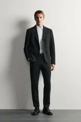 Blazer slim fit de Zara en color negro, confeccionado con mezcla de viscosa. Cuenta con cuello de solapas de muesca, cierre frontal de un botón, bolsillos con solapa en la cadera y un bolsillo de vivo en el pecho.