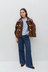 Saco de punto color bordó con bordados artesanales de flores en tonos rosados. Presenta un cuello con detalle de volados en color crema y cierre frontal con botones. De silueta amplia y cómoda.