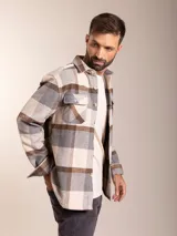 Camisa de franela a cuadros en tonos beige, gris y marrón, con corte regular fit, cuello clásico, cierre de botones frontales y dos bolsillos con solapa en el pecho.