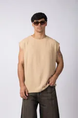 Musculosa oversize de tejido texturado color crema, con cuello redondo y terminaciones deshilachadas en las sisas. Presenta una costura central vertical en la espalda.