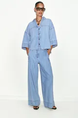 Jeans de tiro medio con corte wide leg y pinzas delanteras. Presenta bolsillos frontales, bolsillos de plastrón en la parte trasera, cierre frontal con cremallera, botón interior y ganchos metálicos.