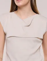 Buzo sin mangas de punto fino color beige, con calce al cuerpo y escote volcado estructurado con solapa superpuesta en el pecho.