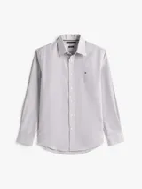 Camisa de manga larga para hombre, con cuello clásico y cierre de botones. Presenta un diseño de rayas verticales finas en tonos blanco y azul oscuro. Cuenta con el logo de Tommy Hilfiger bordado en el pecho.