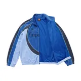 Campera deportiva de terciopelo Supreme x Umbro en color azul, con cuello alto, cierre frontal completo y bolsillos laterales. Cuenta con paneles en distintos tonos de azul y celeste, líneas curvas decorativas, y los logotipos de Umbro y Supreme bordados en el pecho junto con el escudo del Club Nacional de Football.