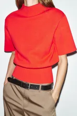 Top de punto liso color rojo, con cuello subido, manga corta con hombreras y bajo acabado en rib.