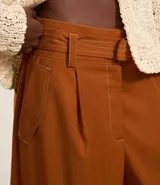 Pantalón pantalona de tiro alto en color marrón, confeccionado en sarga. Cuenta con corte amplio y viene acompañado de un cinturón con hebilla redondeada.