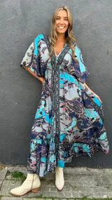 Vestido midi de seda con estampado paisley en tonos turquesa, azul marino, rosa y amarillo. Cuenta con mangas cortas fluidas y diseño amplio.