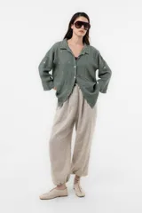 Camisa de lino verde militar con calce relajado, cuello clásico, mangas largas y delicados bordados florales dispersos en la prenda. Cuenta con cierre frontal de botones.