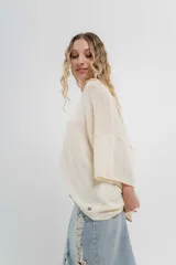 Sweater oversize de tejido liviano color blanco roto, con textura semi traslúcida, escote redondo y mangas amplias estilo murciélago.