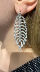 Caravanas colgantes con diseño de hoja, elaboradas con estructura metálica plateada y engarzadas con múltiples cristales brillantes.