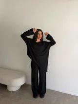 Conjunto gris melange compuesto por un buzo de cuello bote amplio y corte asimétrico con bolsillos, y un pantalón largo de corte recto y holgado.