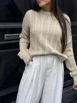 Sweater color crema tejido con diseño en ochos y cuello redondo.