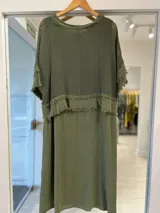 Vestido midi color verde militar, con superposición de tejido de red en la parte superior y detalles de flecos en los bordes de las mangas y el canesú.