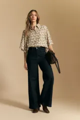 Jean de tiro alto y pierna ancha, confeccionado en denim azul oscuro con costuras a contratono. Presenta un diseño de corte recto y holgado.