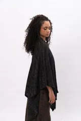 Ruana tejida de punto en mezcla de algodón y lurex, con acabado brillante. Presenta un diseño holgado con escote en V y etiqueta de cuero sintético con logo de la marca en el frente.