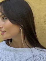 Aro colgante plateado, tipo argolla, del cual caen múltiples tiras finas de strass brillantes.