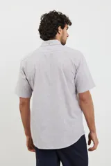 Camisa de manga corta a rayas verticales color celeste y blanco, con cuello abotonado y bolsillo en el pecho.