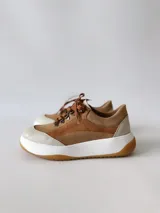 Zapatillas deportivas de cuero color camel con cordones marrones y suela blanca.