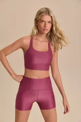 Top deportivo color borgoña, de compresión media, con breteles finos cruzados en la espalda y copas removibles.