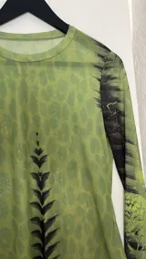 Top de microtul verde con estampado abstracto en tonos verdes y negros, de mangas largas y cuello redondo.