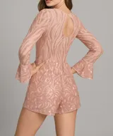 Mono corto de fiesta color rosado con lentejuelas, mangas largas acampanadas y escote redondo.