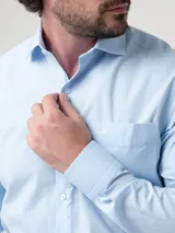 Camisa de manga larga RKF modelo Easysolid, color celeste, confeccionada en popelina de algodón, con cuello clásico, cierre frontal de botones y bolsillo en el pecho con logo bordado.