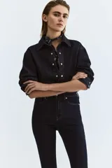 Jean de cinco bolsillos en denim oscuro, con leve elasticidad. Corte ajustado de tiro alto, ceñido desde la cintura hasta las piernas extraajustadas.
