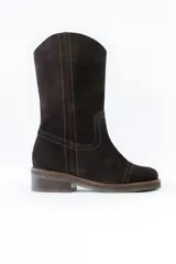 Bota de caña media confeccionada en cuero gamuzado color negro, con costuras a la vista en tono contrastante. Presenta un detalle de cadena metálica plateada con dijes colgantes en forma de llaves y candados alrededor del tobillo. Cuenta con un taco cuadrado de madera y suela de goma.