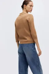 Top corto color tostado en tejido de punto acanalado fino, con cuello tipo polo, tapeta de tres botones y manga tres cuartos. Cuenta con remate acanalado en puños y bajo.