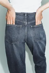 Jeans de tiro alto con corte mom fit, cinco bolsillos y cierre frontal con cremallera y botón metálico.