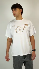 Remera blanca de corte holgado con estampado gráfico en color marrón en el pecho, que incluye una letra D central, estrellas y un globo terráqueo.