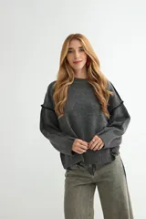 Buzo de tejido de punto color gris oscuro, con cuello redondo, mangas largas con costuras decorativas visibles y puños acanalados.