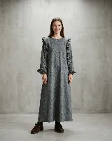 Vestido midi de paño de lana gris, con corte evasé, cuello redondo y mangas largas con volados decorativos en los hombros y puños. Cuenta con bolsillos laterales.