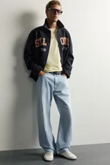 Jeans de denim de algodón en color azul con efecto desgastado, tiro medio y corte recto de ajuste holgado (loose fit). Cuenta con diseño clásico de cinco bolsillos y cierre frontal con cremallera y botón.