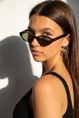 Lentes de sol con armazón ovalado de acetato negro y micas oscuras.