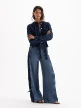 Jeans Roses Bow de tiro medio y calce holgado, con pierna amplia y lavado azul intermedio. Cuenta con recortes laterales en contraste y detalles de lazos regulables en los tobillos.