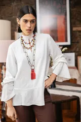 Blusa blanca de textura arrugada, con cuello alto, abertura frontal tipo gota y mangas largas acampanadas con detalle de frunces.