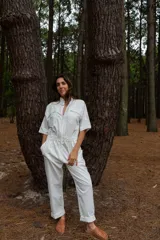 Mono blanco de gabardina de algodón, corte clásico con cierre frontal, pantalón largo con bolsillos, manga corta y cintura fruncida en la espalda.