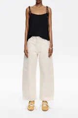 Pantalón vaquero de algodón orgánico color blanco crudo, tiro medio, corte barrel ancho y largo tobillero. Presenta bolsillos redondeados delanteros y bolsillos plastrón traseros.