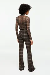 Pantalón flare de tul estampado con patrón de cuadros en tonos marrones y negros, tiro alto y silueta ajustada que se ensancha en la parte inferior.