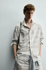 Camisa regular fit confeccionada en tejido de algodón con diseño de cuadros en tonos celestes y beige, cuello con botones, manga larga con puño abotonado y bolsillo de parche en el pecho.