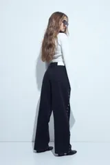 Jean de corte recto y calce relajado color negro, confeccionado en denim estructurado, con detalles de tachas metálicas plateadas en los laterales.